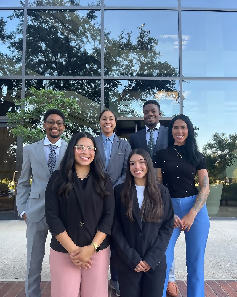 Seven Social Standard team members outside a glass-fronted office building