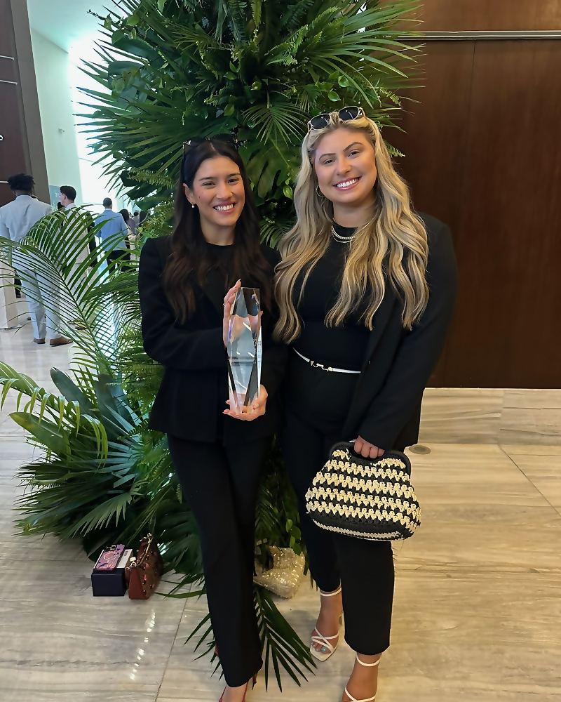 Two Social Standard team members holding a glass award